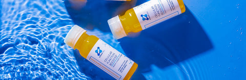 Strong Cell Bottles floating in blue water. Strong Cell, a liquid NADH, CoQ10, and Marine Collagen Supplement